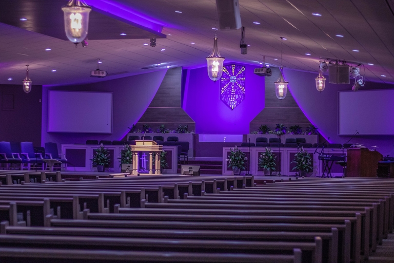 A church with purple lighting and pews, creating a serene ambiance.